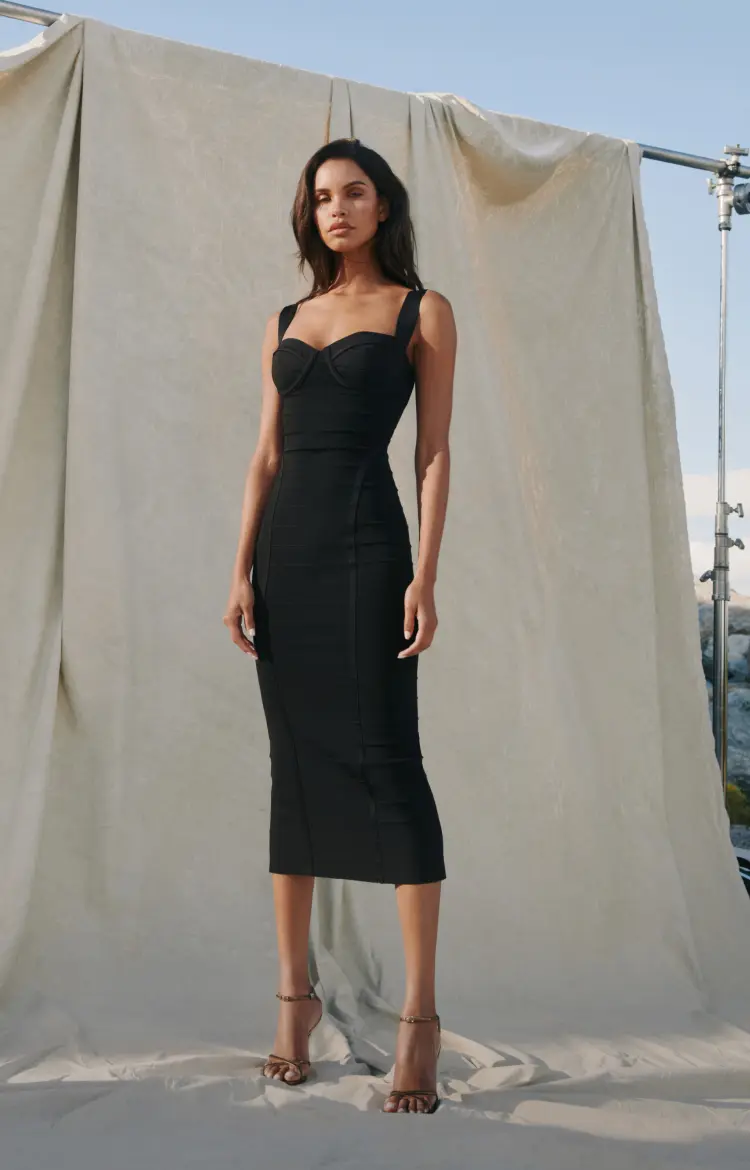 Model is wearing a black bustier bandage dress.